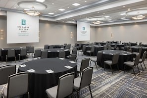 A conference room with round tables and chairs, large banners, and a patterned carpet.