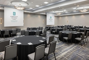 A conference room with round tables and chairs, large banners, and a patterned carpet.