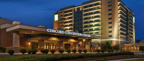 A multi-story hotel with a prominent 'CONCORD CONVENTION CENTER' sign, a landscaped entrance, and a modern architectural design.