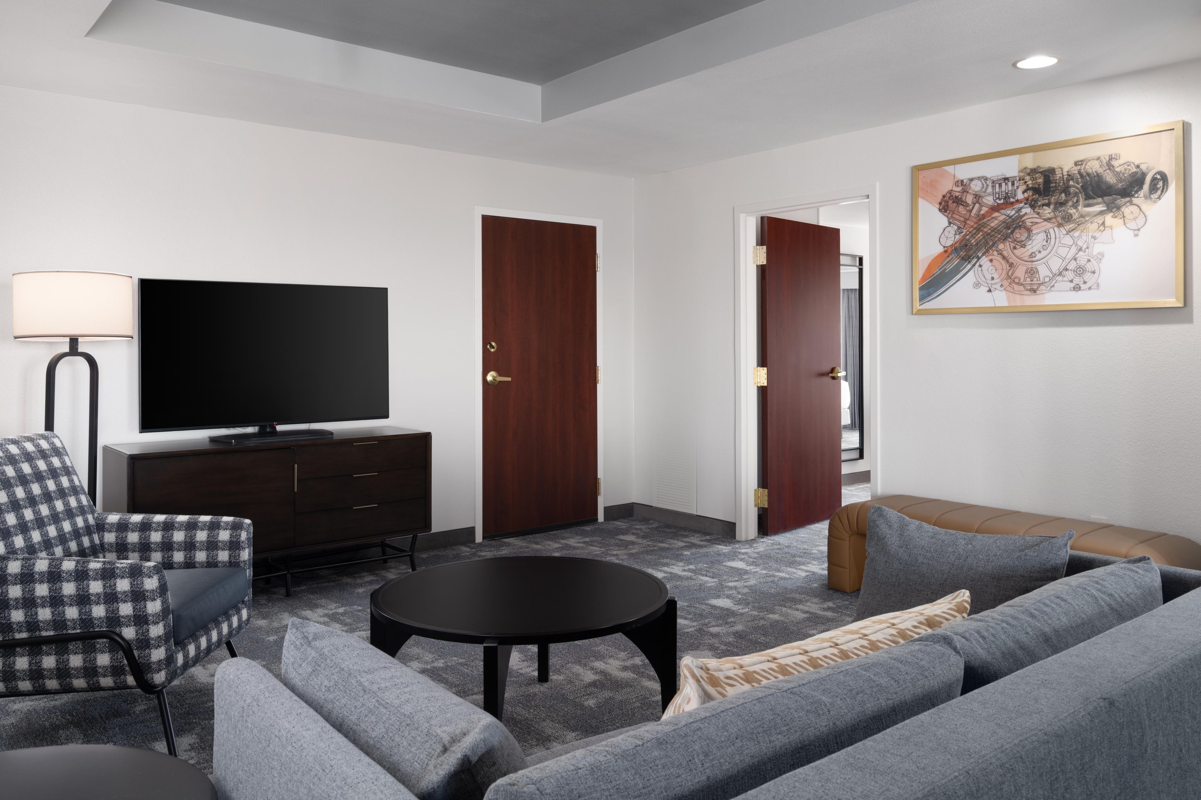 A modern living room with a flat-screen TV, a sofa, a coffee table, and a lamp.