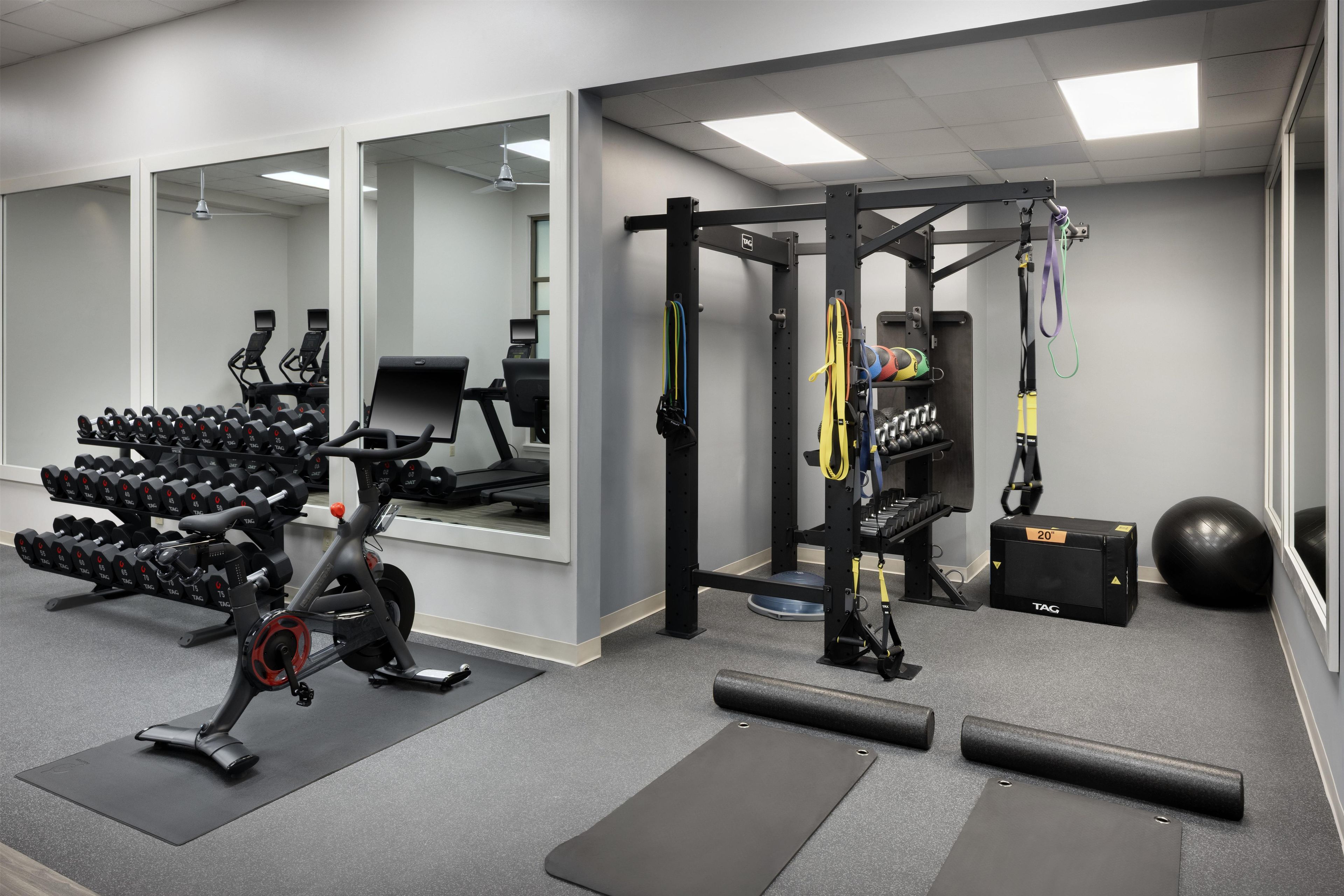 A gym with weightlifting equipment, exercise mats, and a mirror.