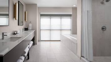 Un baño moderno con un ventanal amplio, una ducha y un tocador con toallero.