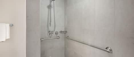 A modern shower area with a handheld showerhead, a handheld shower attachment, and a grab bar for support.