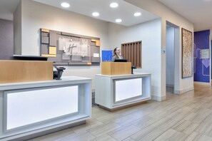 A reception area with two reception desks, a wall-mounted sign, and a blue wall with a geometric pattern.