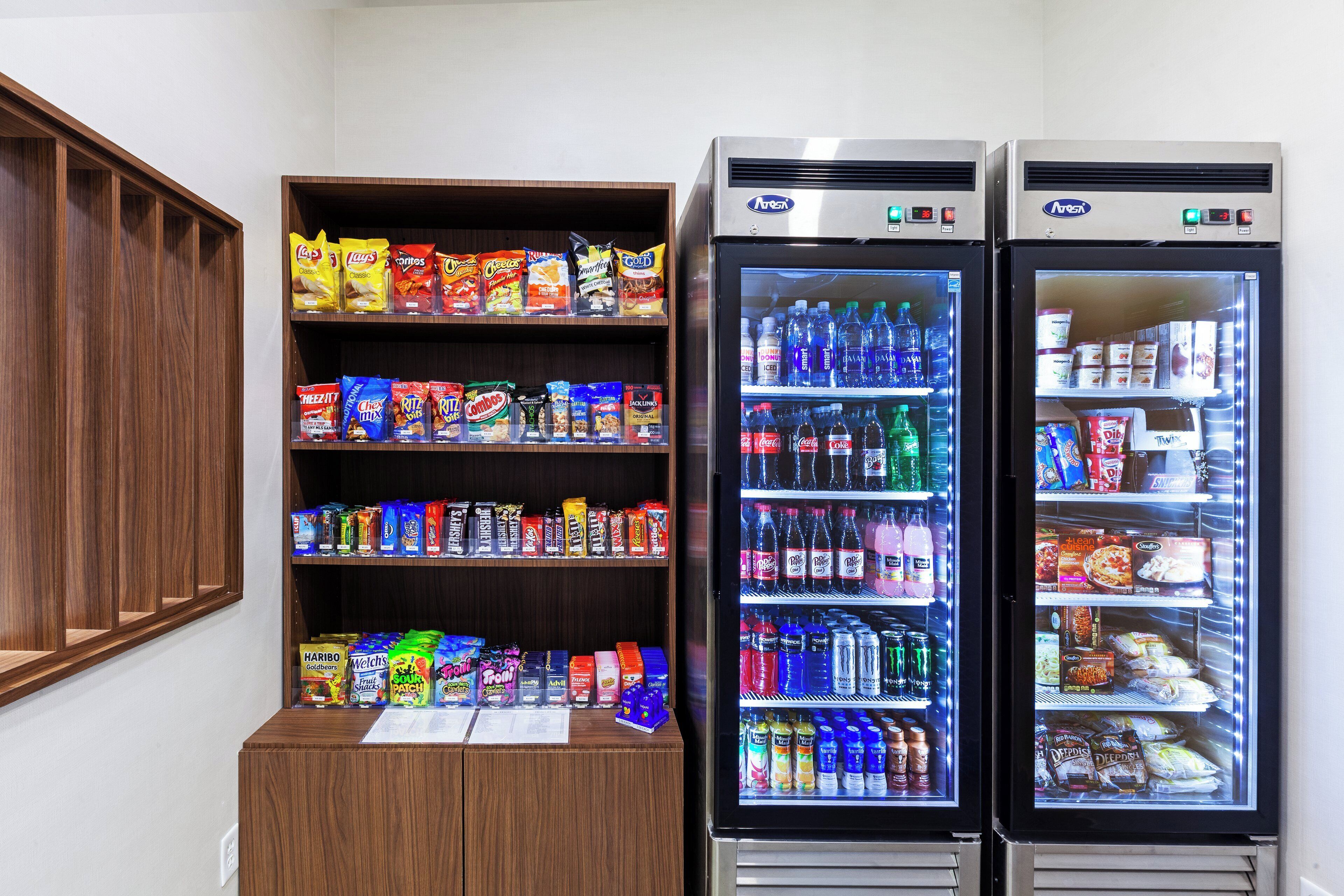 A vending machine with snacks and drinks, and two freezers with frozen items.