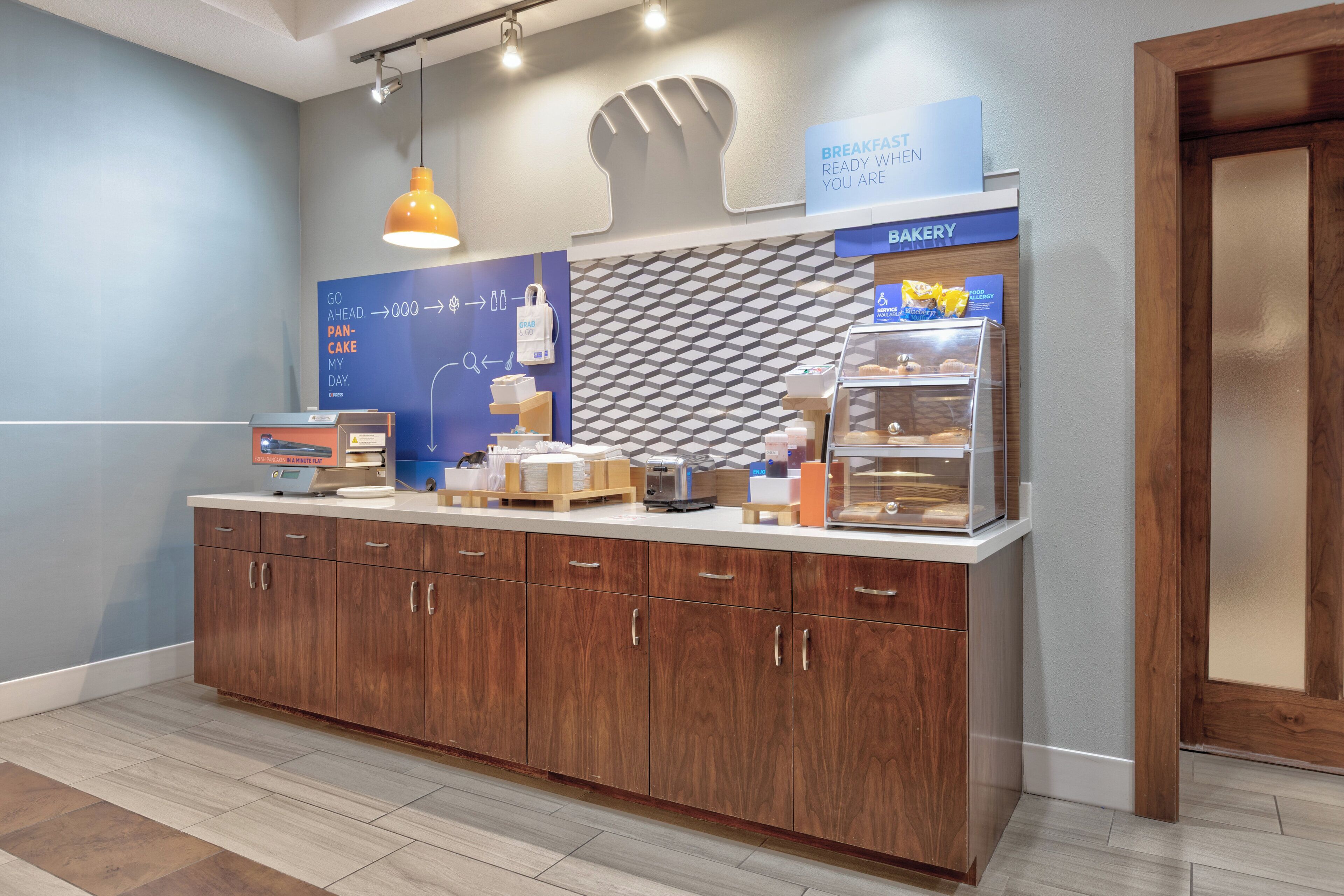 A breakfast counter with a bakery section, a wall clock, and a sign indicating breakfast is ready.