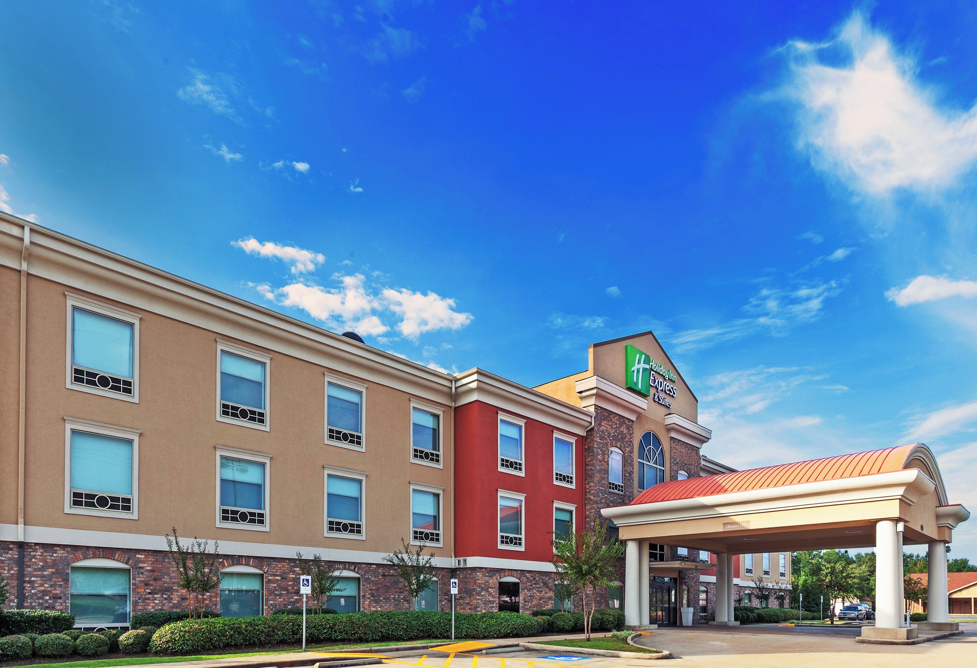 A multi-story hotel with a prominent Holiday Inn Express sign, a covered entrance, and a parking lot.
