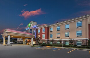 Edificio de Holiday Inn Express & Suites con entrada cubierta, múltiples ventanas y estacionamiento con espacios para discapacitados.