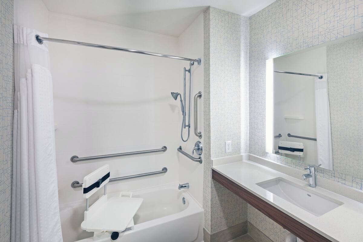A bathroom with a bathtub, a shower, a sink, and a mirror.