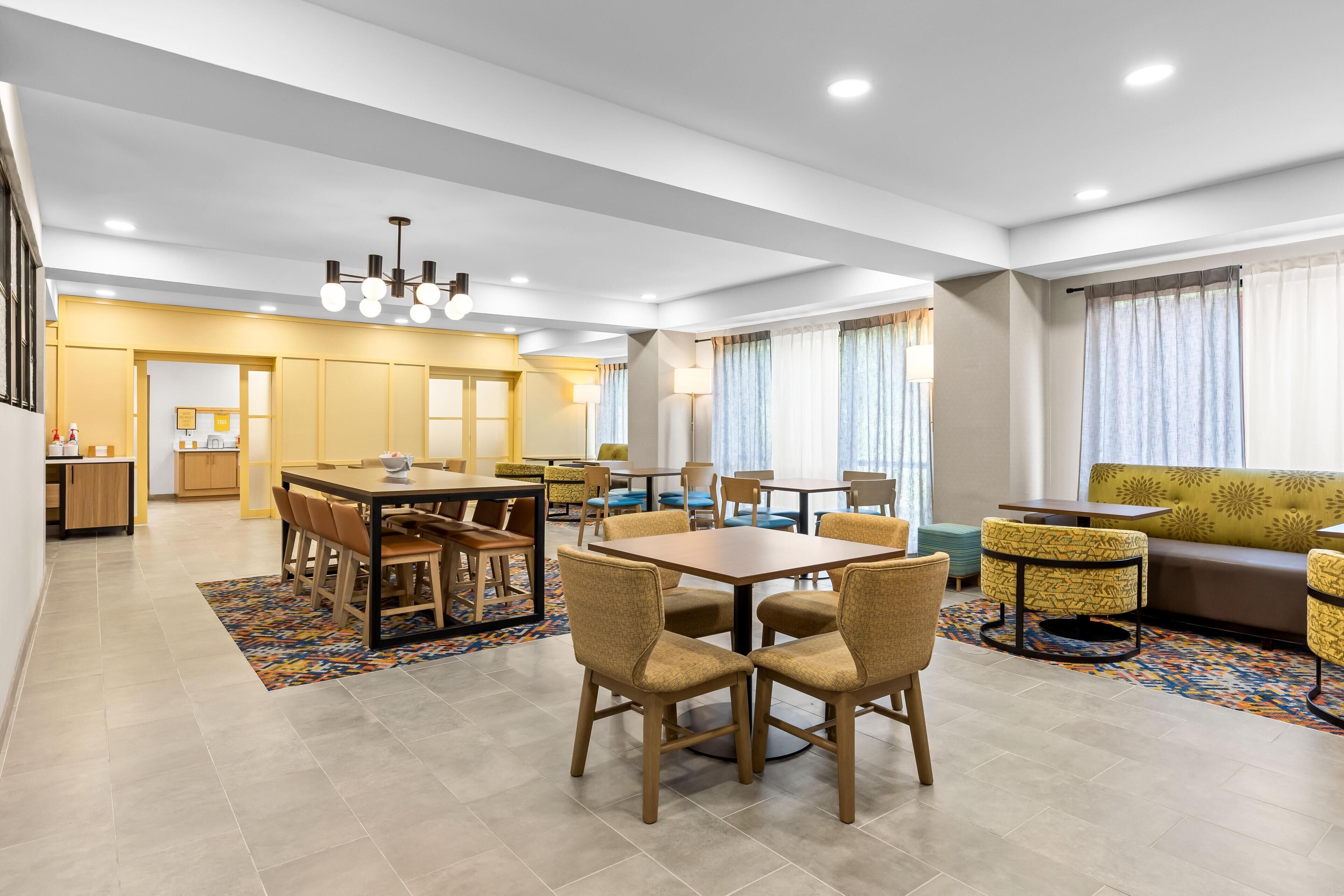 A modern hotel room with a dining area, a sofa, and a staircase.