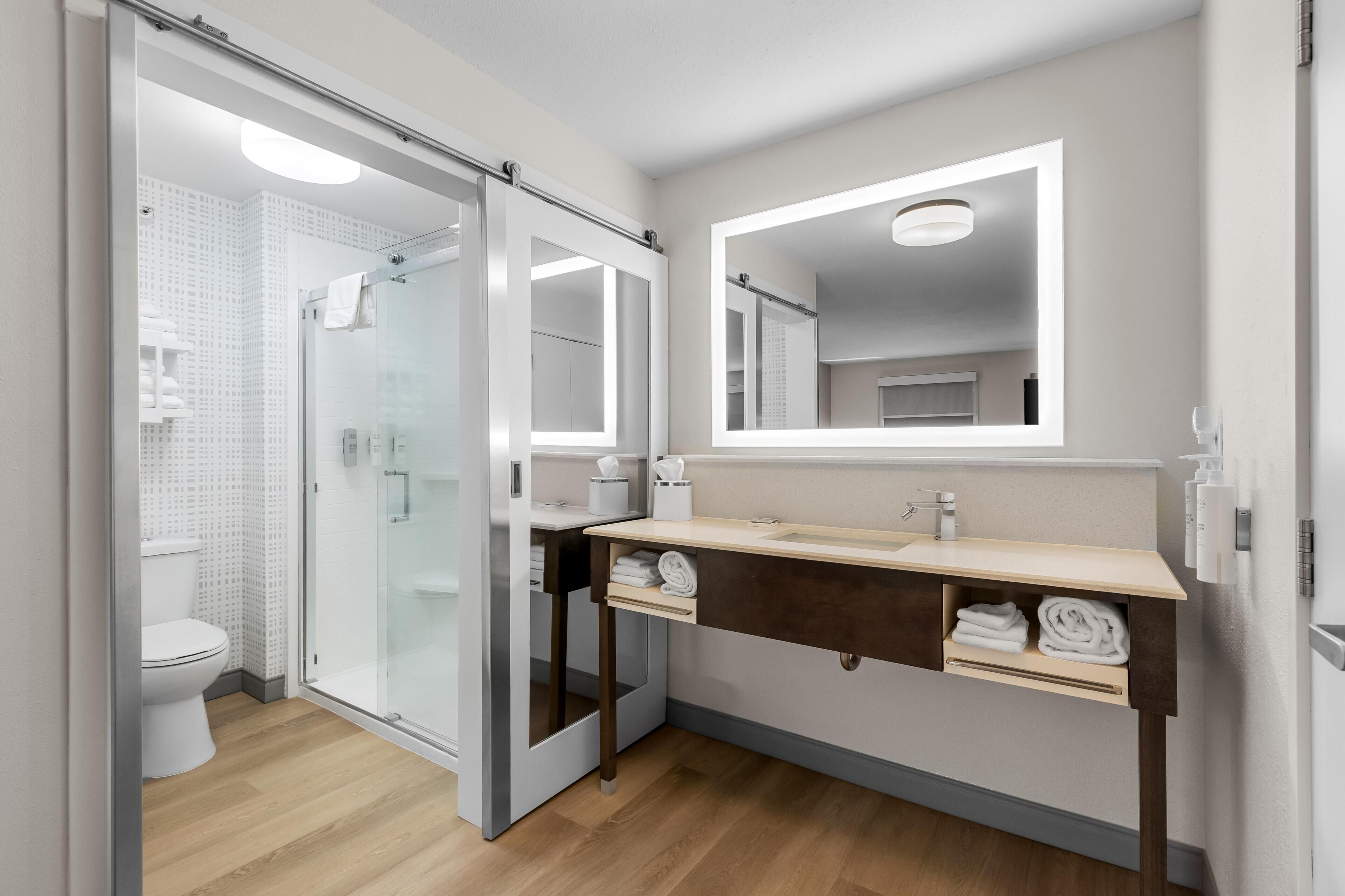 A modern bathroom with a glass shower enclosure, a vanity with a mirror, and a toilet.