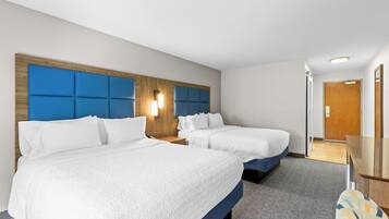 A hotel room with two beds, a wooden headboard, a nightstand, a desk, and a mirror.