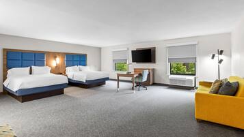 Une chambre d’hôtel avec deux lits, un bureau, une télévision et un canapé.