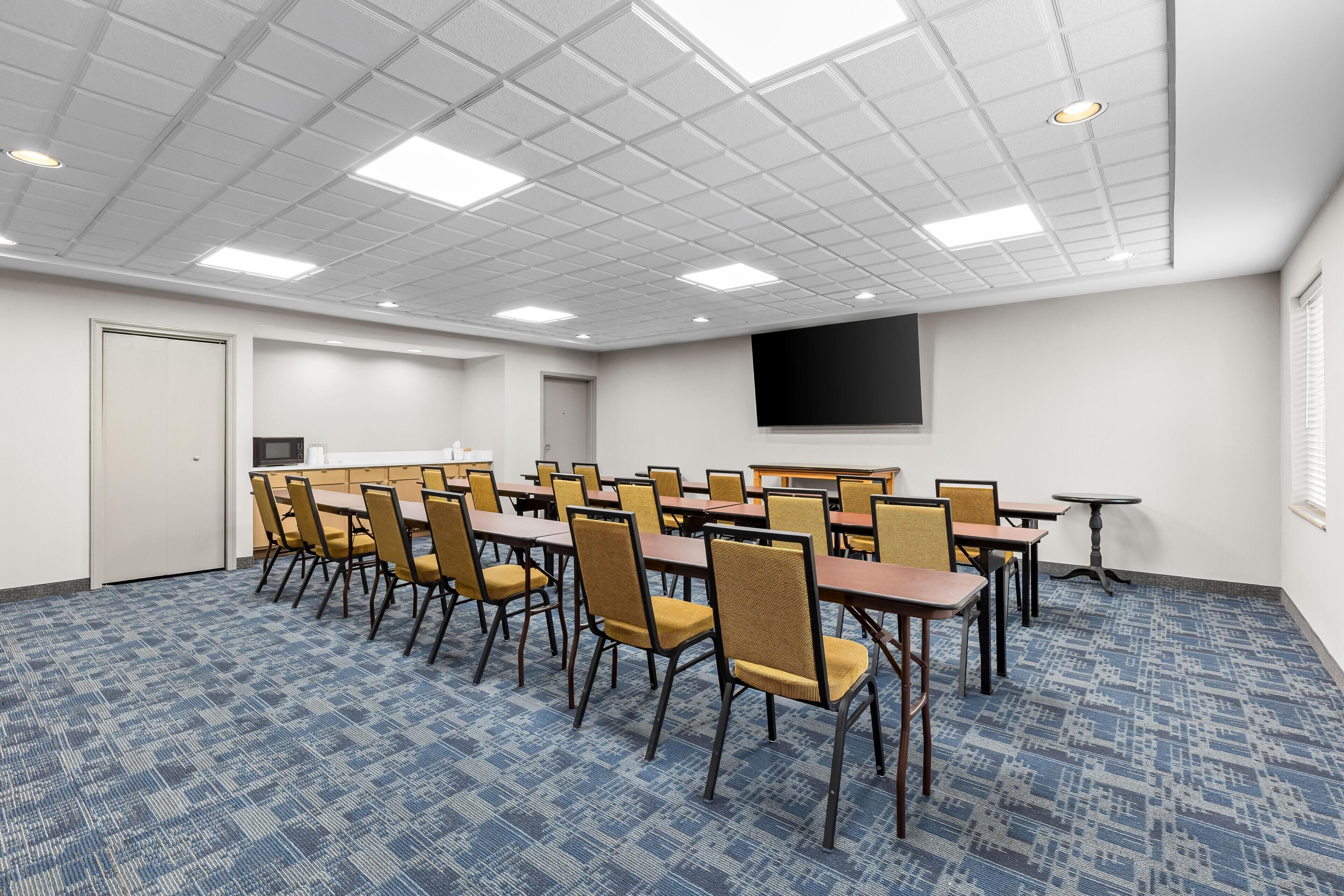 Une salle de conférence équipée d’un téléviseur à écran plat, de plusieurs tables et de chaises.