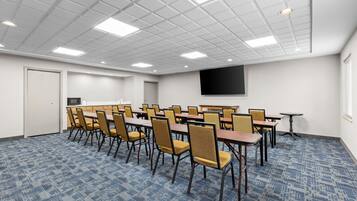 Une salle de conférence équipée d’un téléviseur à écran plat, de plusieurs tables et de chaises.