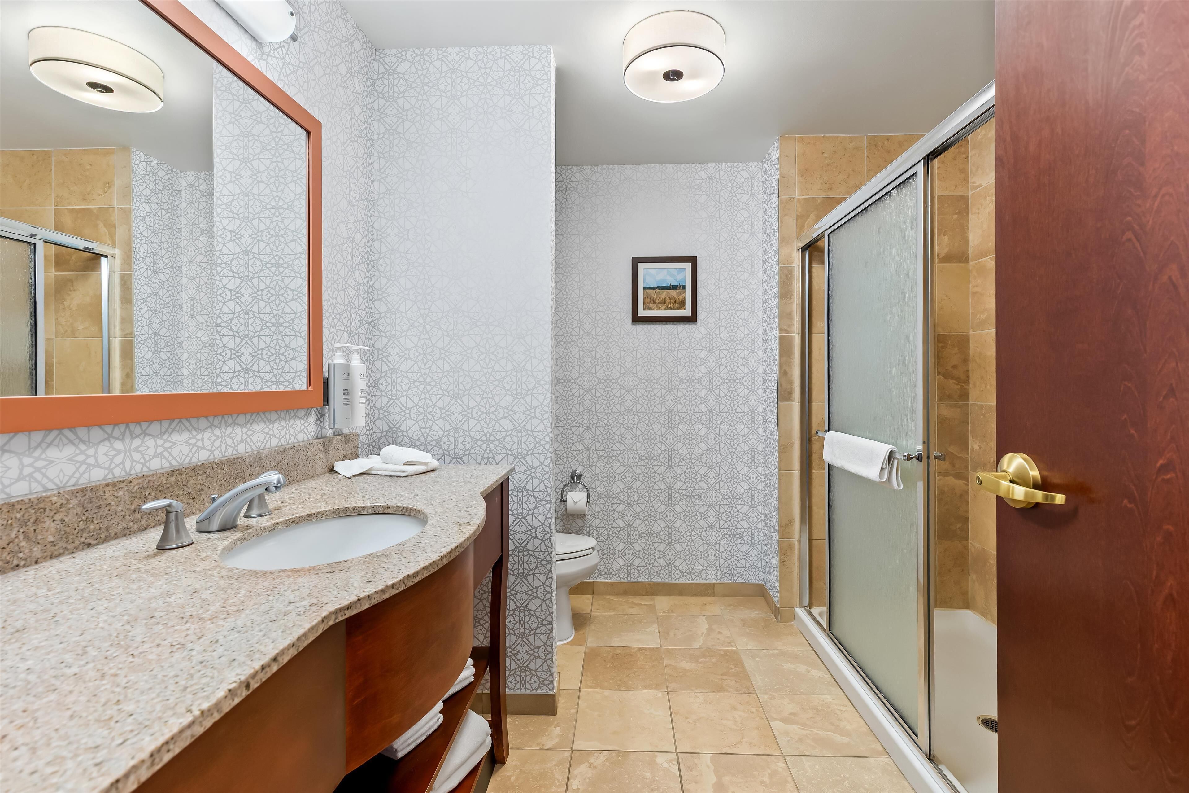 Un baño con lavamanos, espejo y ducha.