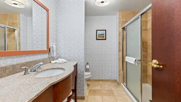 A bathroom with a sink, mirror, and shower.
