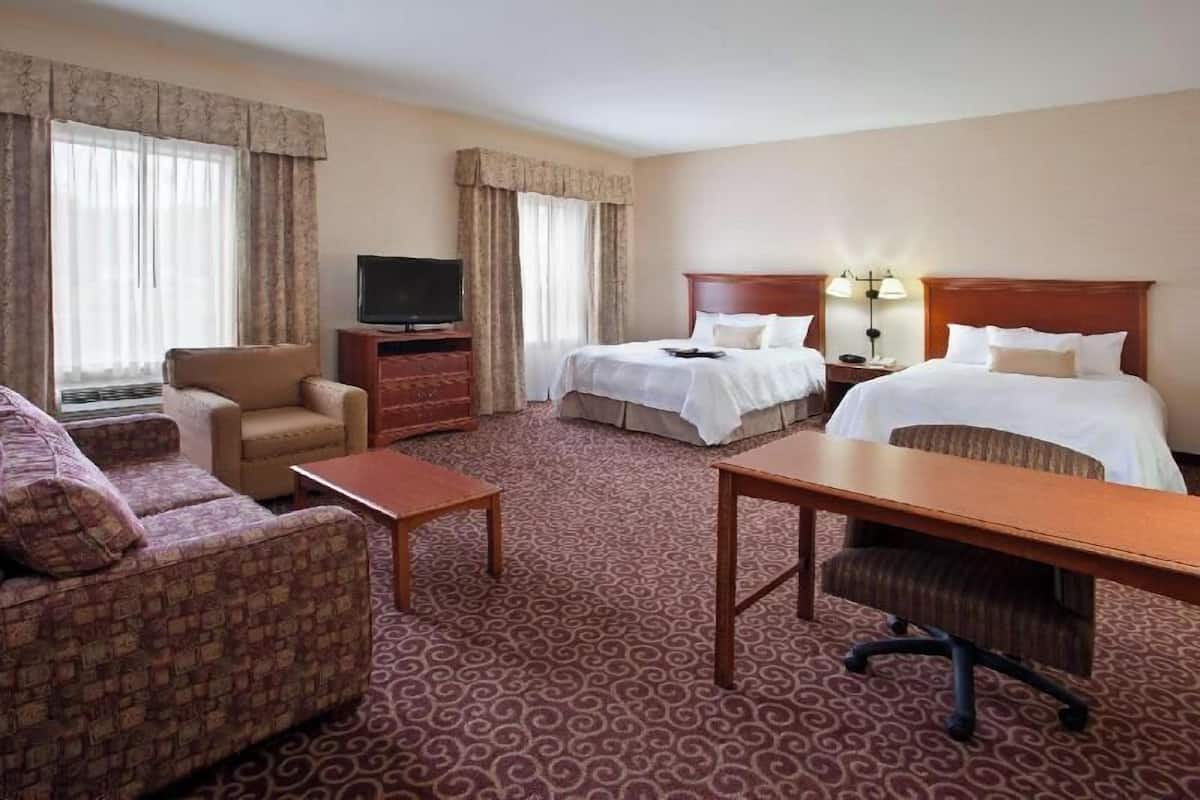 Une chambre d’hôtel avec deux lits, une télévision, un bureau, une chaise et un canapé.