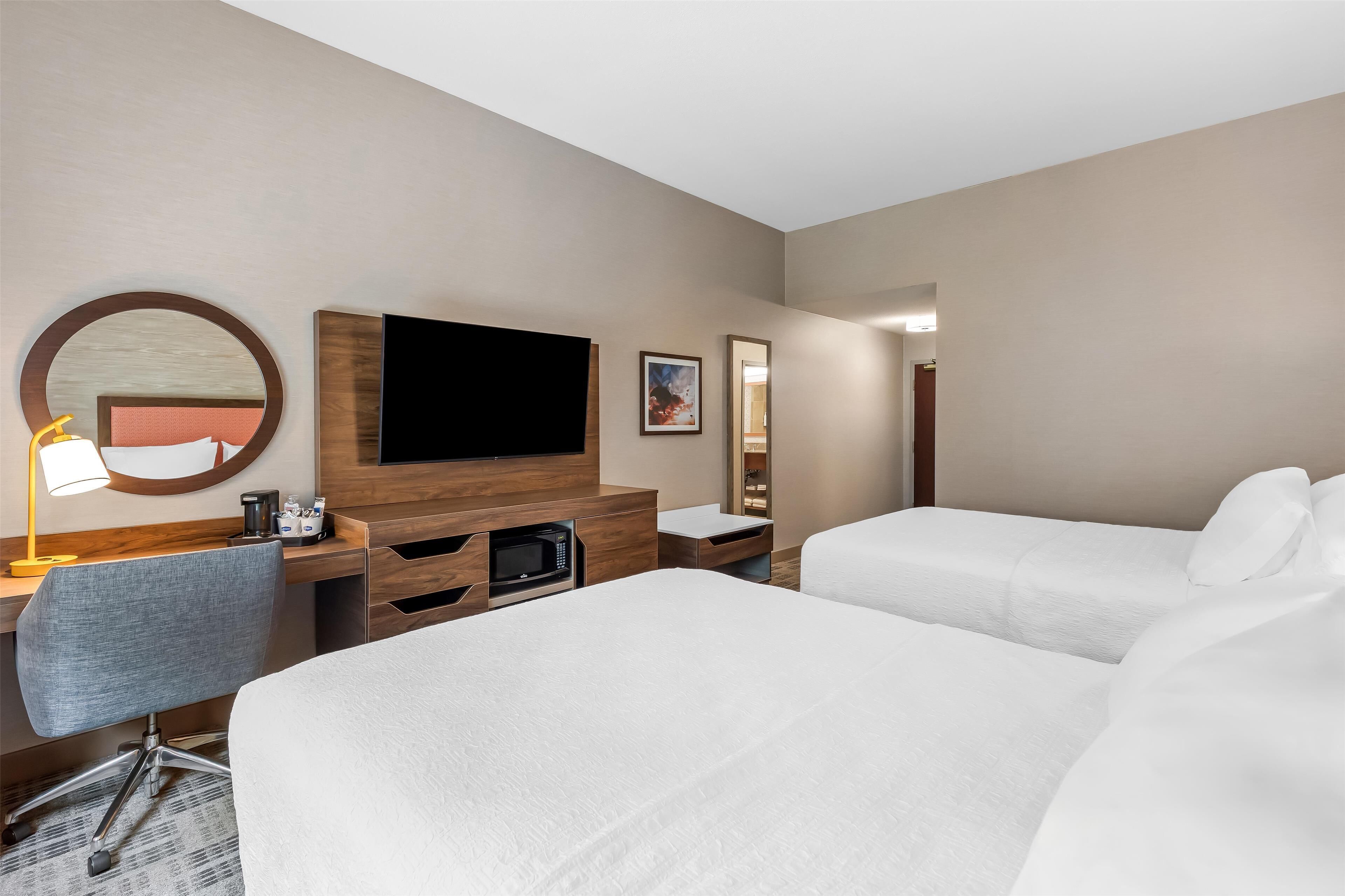 Een hotelkamer met een bed, een bureau met stoel, een televisie en een magnetron.