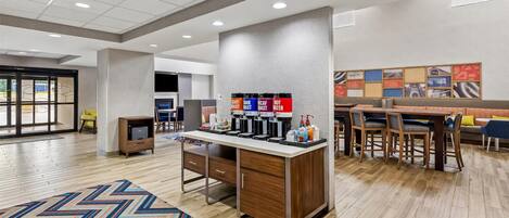 Un hall d’hôtel moderne doté d’un espace café, d’un coin salon et d’une grande fenêtre.