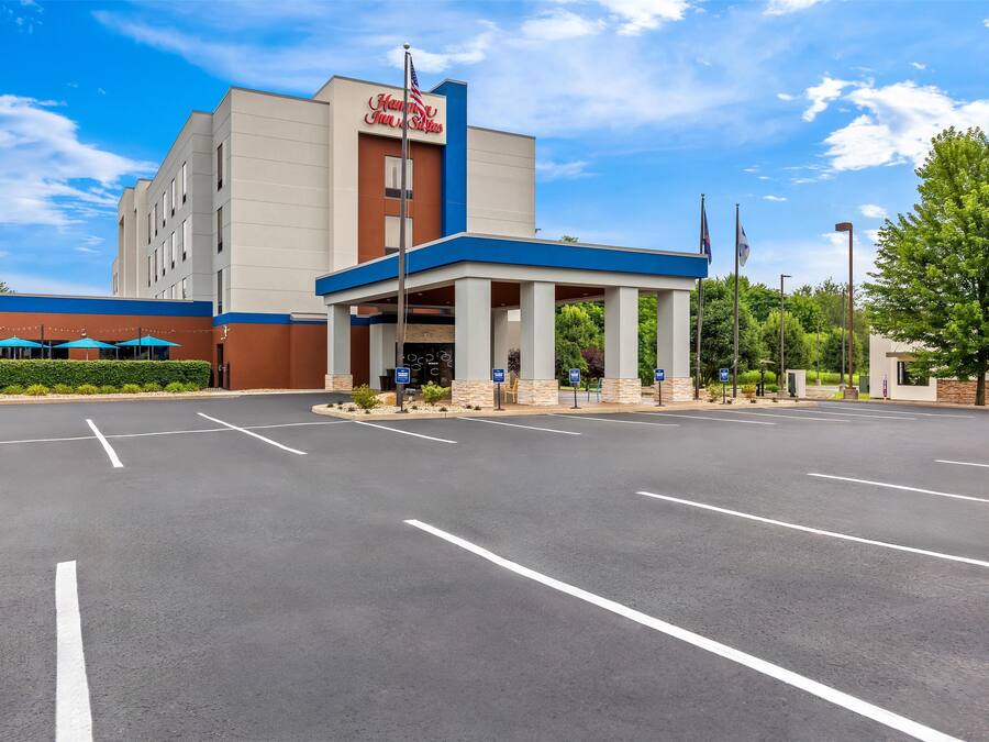 A hotel with a prominent sign, a covered entrance, and a parking lot.
