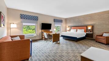 Una habitación de hotel con cama, escritorio, silla, sofá y televisor.