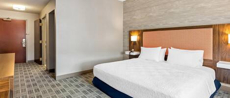 Una habitación de hotel con una cama grande, una mesita de noche, un escritorio y una silla.