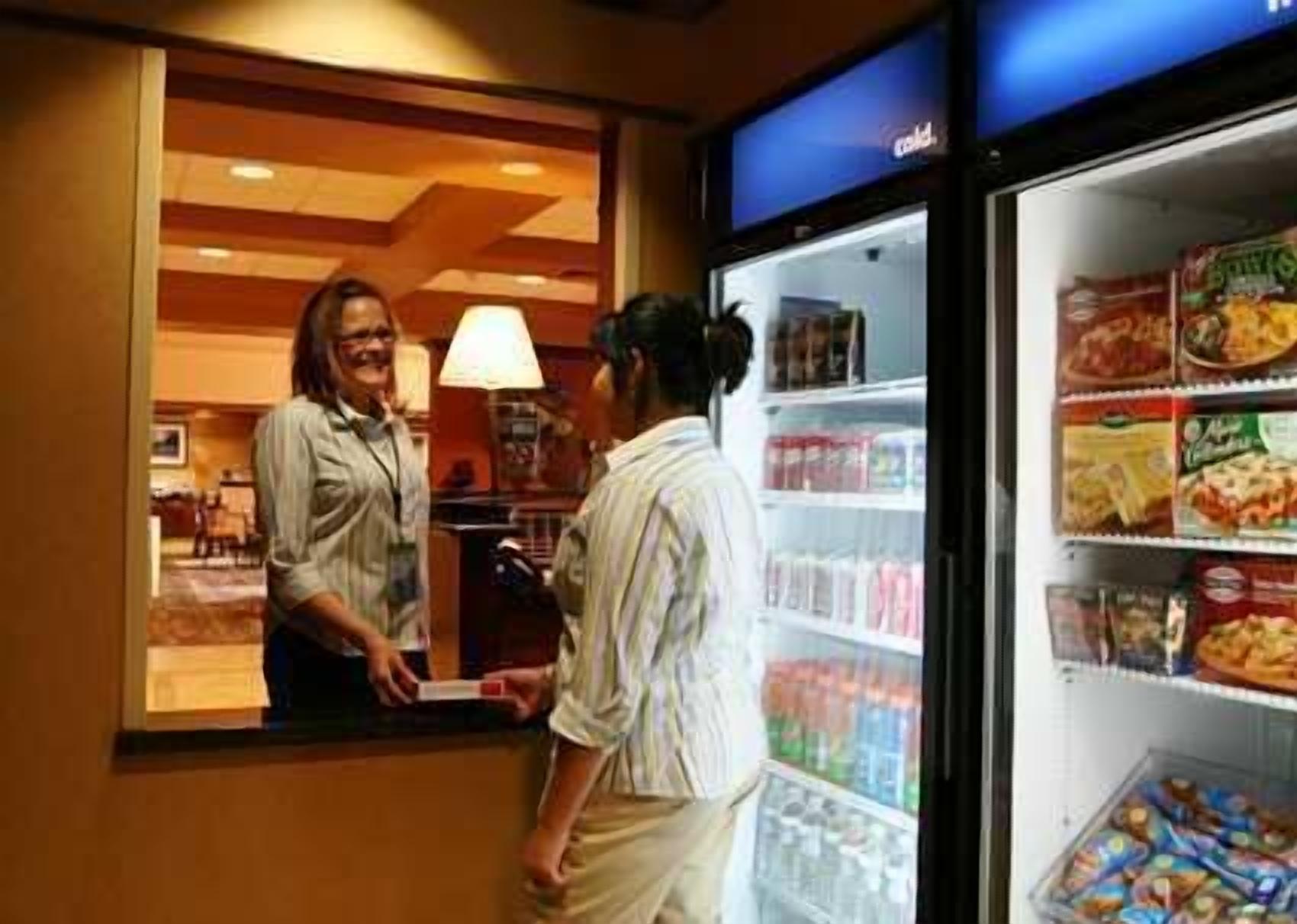 A hotel reception area with a counter and a refrigerator stocked with snacks and beverages.