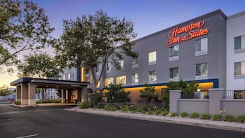A Hampton Inn & Suites building with a modern design, featuring a prominent entrance and a well-lit facade.
