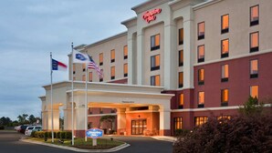 A Hampton Inn hotel with a clear entrance, American and Malaysian flags, and a sign indicating a 12' clearance. - Hampton Inn by Hilton Dunn (Dunn)