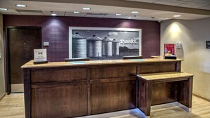 A reception desk with a 'Hilton Honors' sign, a 'thanks' poster, and a 'Man On Duty' sign. - Hampton Inn by Hilton Dunn (Dunn)