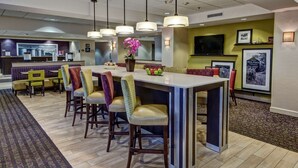 A hotel lobby with a reception desk, a bar area with stools, and a seating area with chairs and a couch. - Hampton Inn by Hilton Dunn (Dunn)