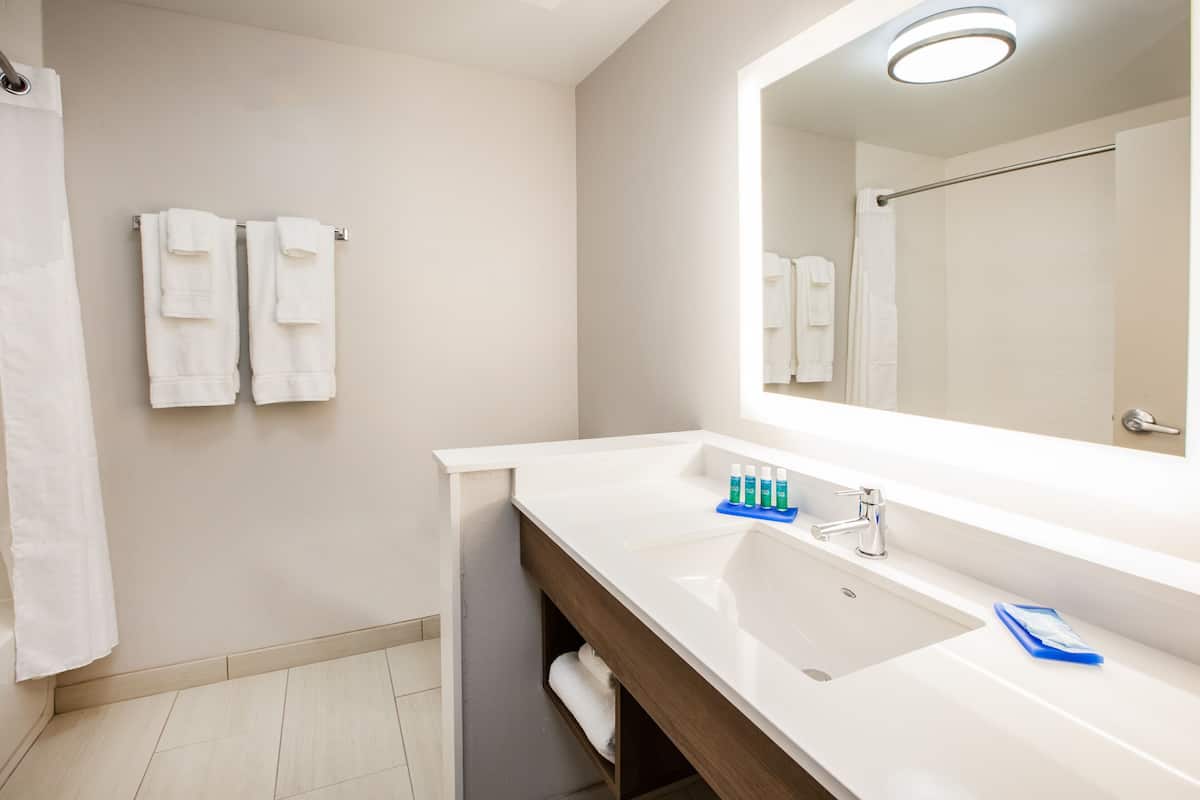 Une salle de bain moderne avec un grand lavabo, un miroir et un porte-serviettes.
