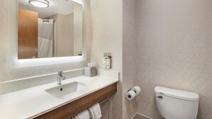 A modern bathroom with a white sink, mirror, and toilet.