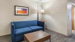A room with a blue sofa, a wooden coffee table, a floor lamp, and a framed picture on the wall.