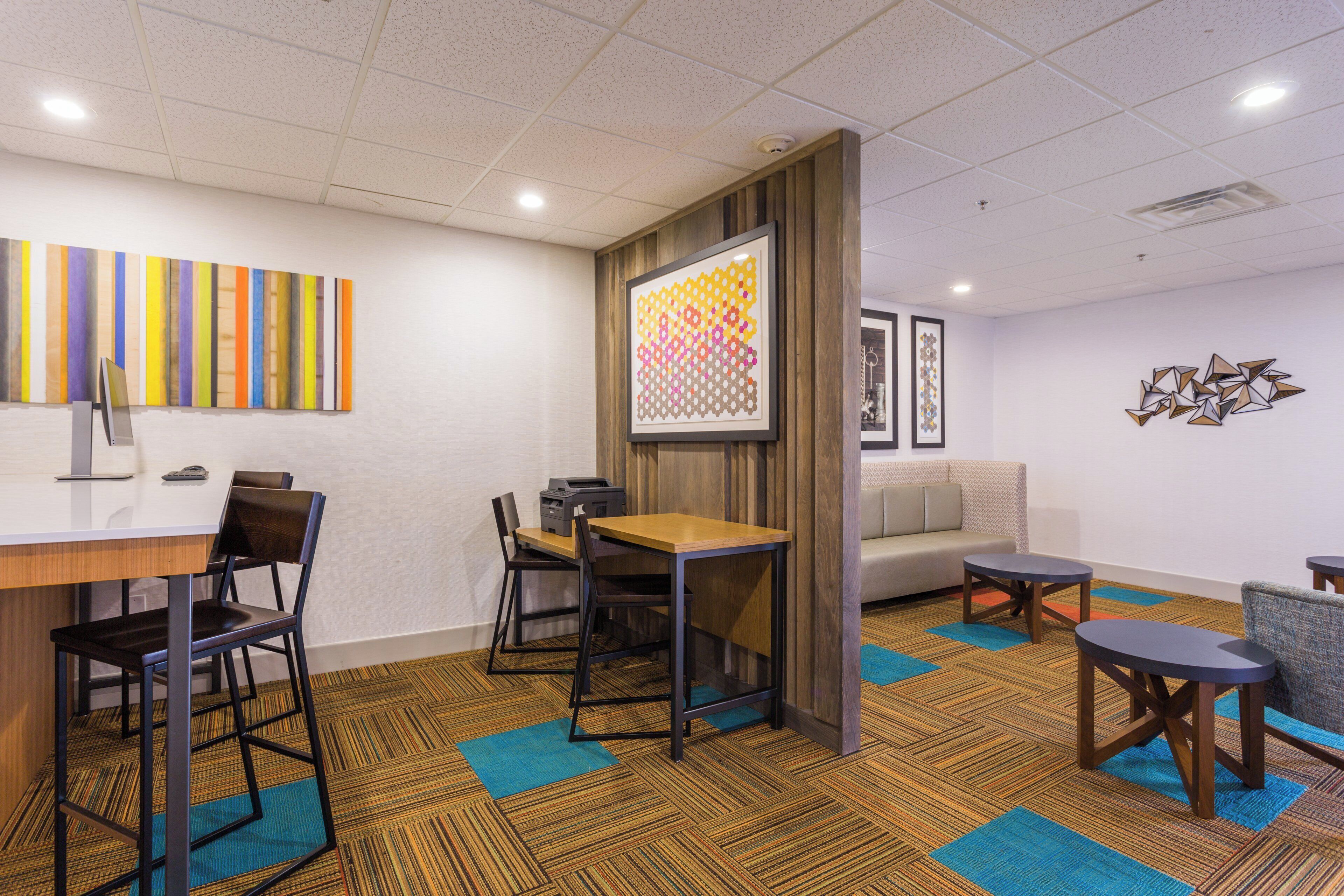 A modern conference room with a long table, chairs, a sofa, and a carpeted floor.