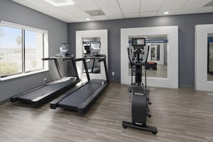 Un gimnasio con cintas de correr, una bicicleta estática y una máquina de pesas.