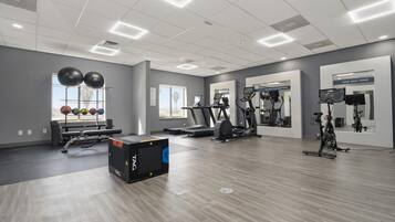 Un gimnasio con equipo de ejercicio, cinta de correr y remo.