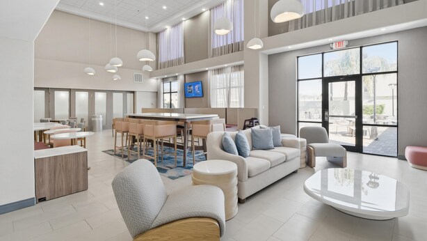 Een moderne hotellobby met een zithoek, een receptiebalie en een groot raam met uitzicht.