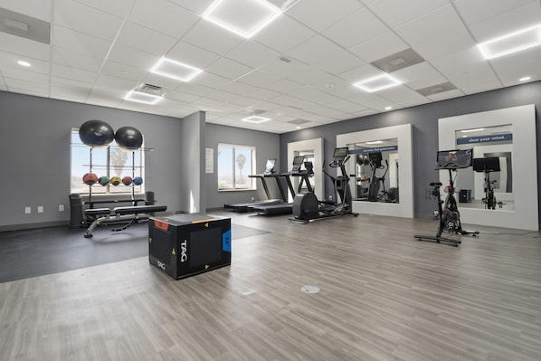Un gimnasio con cintas de correr, elípticas y pelotas de ejercicio.