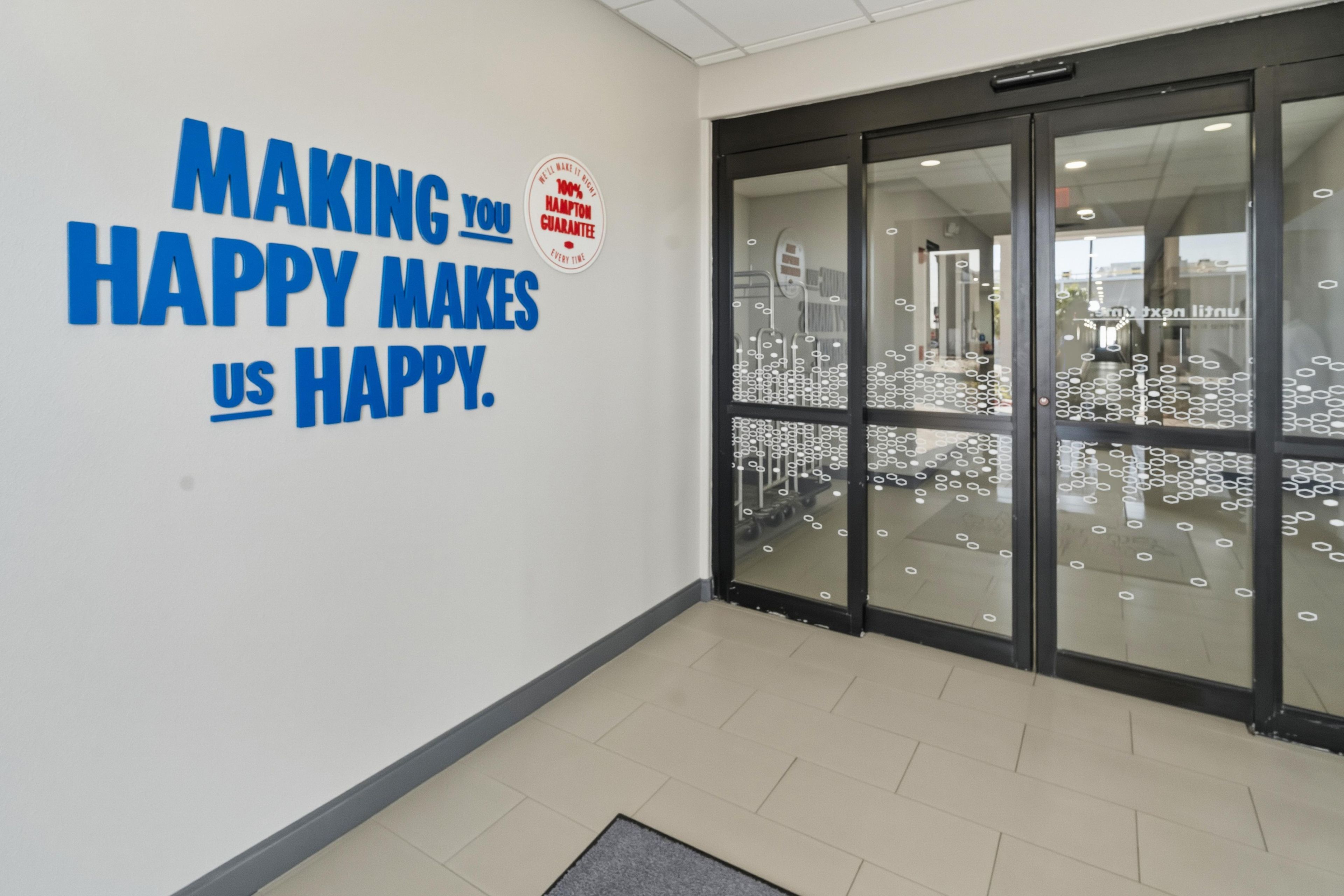 A wall with motivational text and a glass door with circular patterns.