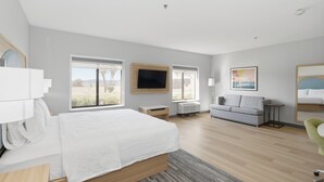 Een moderne hotelkamer met een groot bed, een bank, een televisie en een raam met uitzicht.