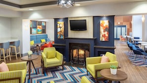 Un área de estar moderna con sofás estampados color amarillo, una chimenea y un televisor de pantalla plana montado encima.