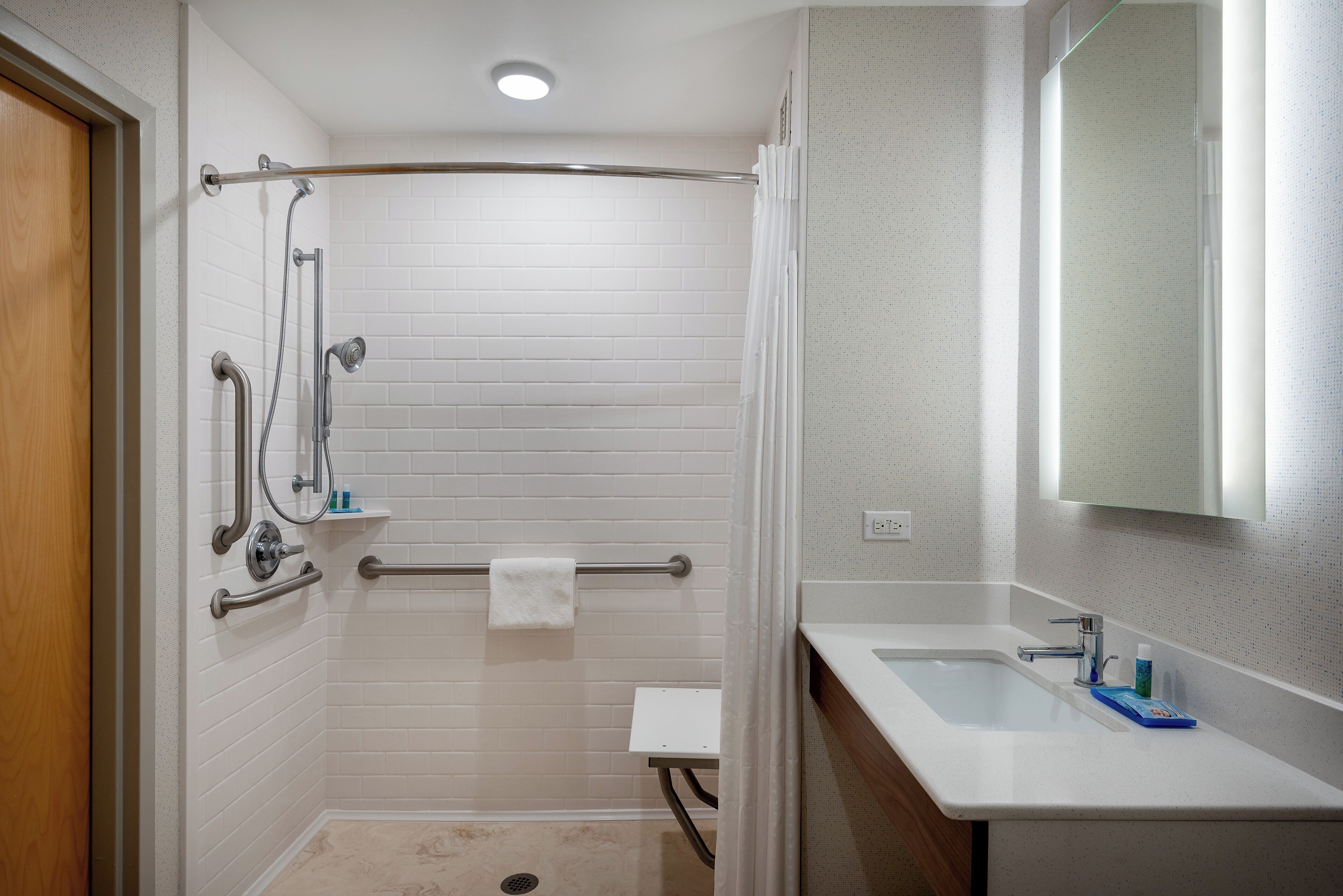 A bathroom with a shower, a toilet, a sink, and a mirror.