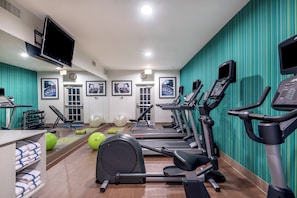Un gimnasio con cintas de correr, pelotas de ejercicio y mancuernas.