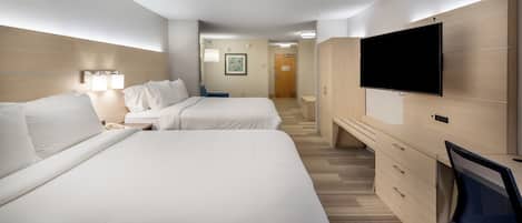 A hotel room with two beds, a desk, a television, and a bathroom visible in the background.
