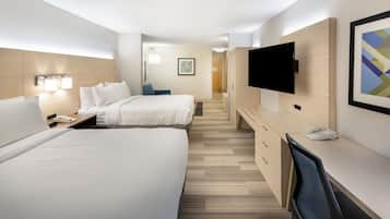 Une chambre d’hôtel avec deux lits, un bureau, une chaise, un téléviseur à écran plat et un téléphone.