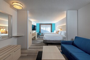 A hotel room with a bed, a desk, a television, and a blue sofa. - Holiday Inn Express & Suites Daphne- Spanish Fort Area by IHG (Daphne)