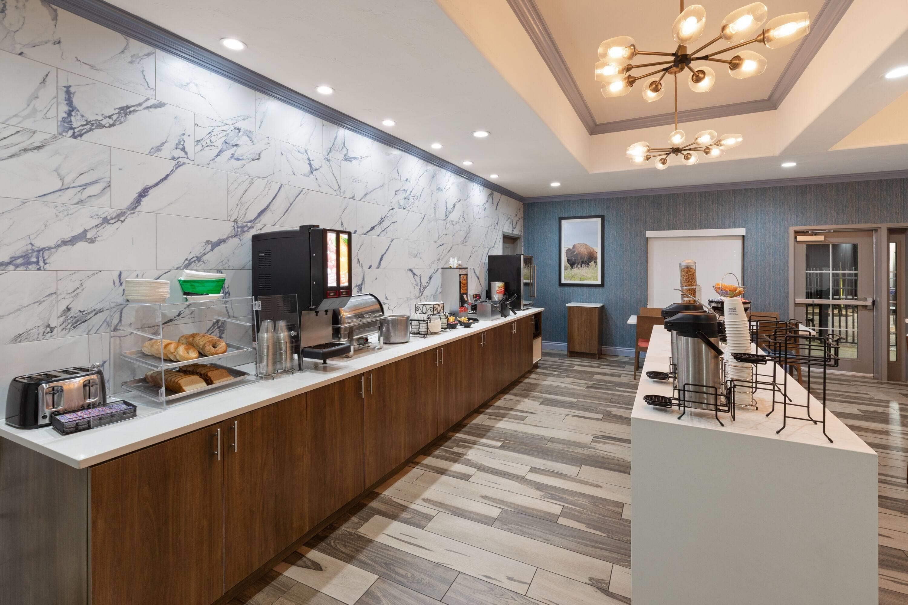 A hotel breakfast area with marble walls, wooden cabinets, and a modern chandelier.