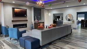 Una sala moderna con un sofá seccional gris, sillones azules y una chimenea.